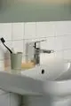 Chromene Waschtischarmatur von Ideal Standard mit einem modernen Design. Zu sehen sind eine Zahnbürste, eine Tube und ein Stück Seife auf einem Waschbecken vor einer gefliesten Wand.